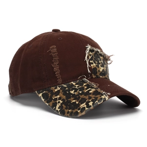 Detail of distressed baseball cap featuring leopard print patches and frayed brim textures