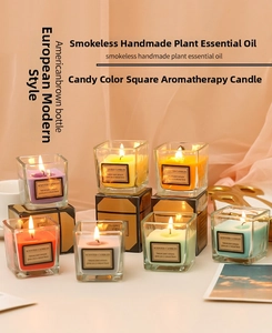 Detailed view of colorful scented candles in square glass jars with elegant gift boxes