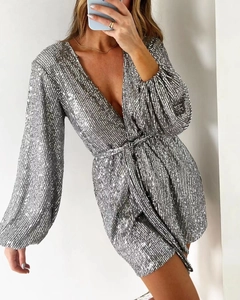 Detail of silver sequined long sleeve dress with deep V-neck and stylish waist tie belt