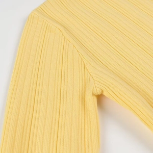 Gros plan sur le tissu en maille jaune montrant la texture côtelée et les détails