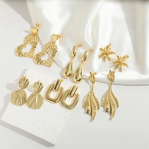 Detail view of assorted gold metal earrings in heart, petal, and geometric shapes