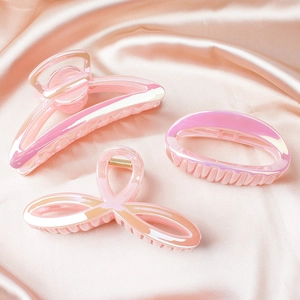 Iridescent pink jelly hair claws with pearl finish on soft silk fabric background