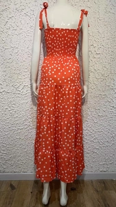 Detail of red polka dot maxi dress featuring tiered skirt and shoulder ribbon ties