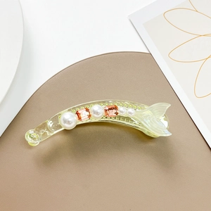Detail of banana hair clip with white pearls and champagne square gems in a fish tail design