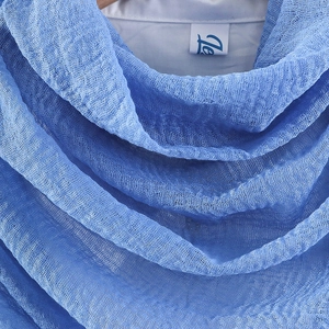 Close-up of blue crinkle cotton scarf fabric texture with soft frayed fringe edges