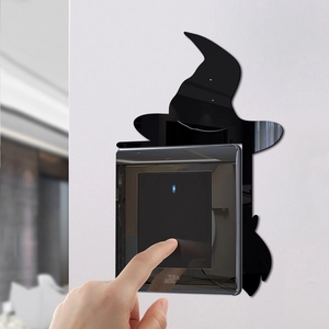 Close-up of a black acrylic witch silhouette wall sticker around a modern light switch
