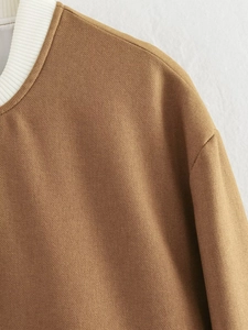 Close-up detail of the brown twill fabric and white ribbed collar on this Y2K bomber jacket