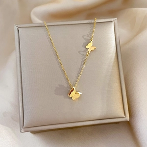 Macro detail of golden butterfly pendants on jewelry box with silk texture background