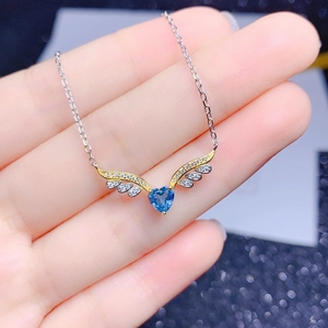 Nahaufnahme der herzförmigen blauen Steinkette mit Engelsflügel-Design in der Hand