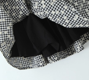 Detail of black and white plaid dress fabric with small white flower embroidery