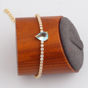 Detail of light blue teardrop gemstone bracelet with gold plating and cubic zirconia