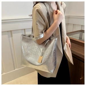 Detail of silver crocodile pattern tote bag with glossy texture and slim shoulder strap