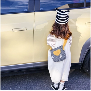 Détail du sac bandoulière à damier avec cœur en peluche jaune et bonnet assorti