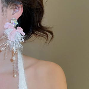 Detail of earring with pink bow, white feather, and pearl chain on female model