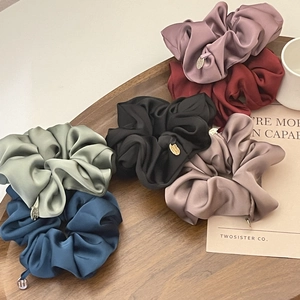 Detail of luxury satin scrunchies in muted vintage colors with elegant metal charms