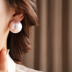 Close-up of a large pink pearl stud earring worn by a model for a chic and stylish look