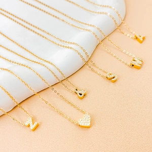 Golden hip hop alphabet necklaces with cubic zirconia pendants on white wave display