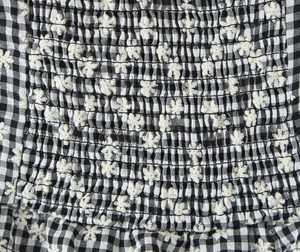 Close-up of black and white plaid cotton fabric with white floral embroidery detail