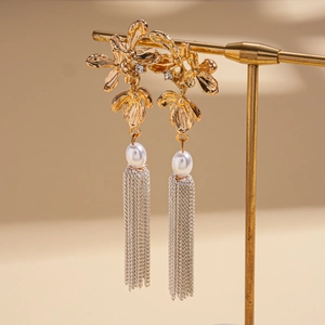 Détails de boucles d'oreilles fleuries avec strass brillants, perles et glands argentés