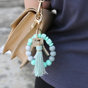 Silicone bead wristlet keychain with turquoise tassel and LOVE charms on a beige handbag