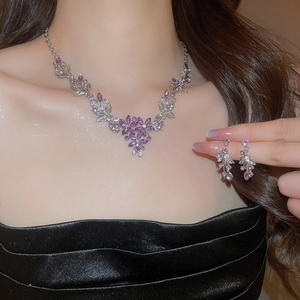 Close-up of elegant purple floral necklace and earring set on a model with soft lighting