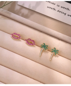 Detailed macro view of gold plated lip and palm tree earrings with colorful zircon pavé