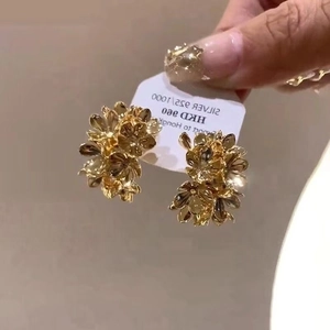 Makroaufnahme goldener Blumenohrringe aus 925er Silber mit gestuften Metallblütenblättern