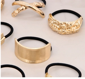 Detail view of irregular gold alloy charms on black elastic hair ties with lava textures
