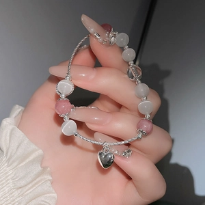 Nahaufnahme von Katzenaugen-Perlenarmband mit Herzanhänger am Handgelenk einer Person