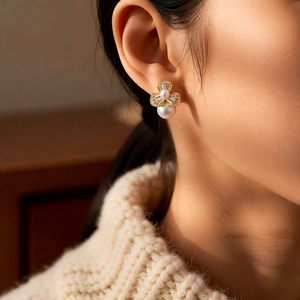 Close-up of elegant flower pearl earrings with crystals on a model wearing cream knitwear