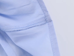 Detailed close-up showing double-needle lockstitch and inner seam of the blue poplin shirt