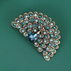 Detail of peacock brooch with blue rhinestones and pear-cut gem on antique bronze metal