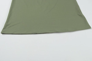 Detail eines salbeigrünen Kleidsaums mit gleichmäßiger Flachstichnaht und Stofftextur