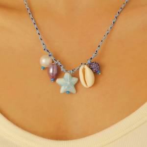 Dettaglio della collana boho con conchiglia e stella marina e corda blu indossata