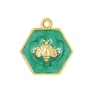 Détail macro du pendentif abeille hexagonal avec émail pailleté vert et placage or