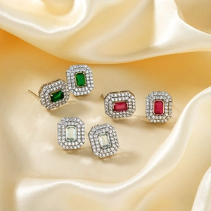 Macro shot of rectangular zircon stud earrings in green, pink and blue with silver finish