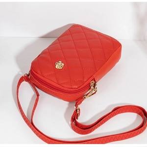 Close-up of quilted red phone bag featuring a golden rose-shaped metal lock and zipper