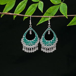 Detail of silver alloy bohemian earrings with green enamel and metal bead tassels