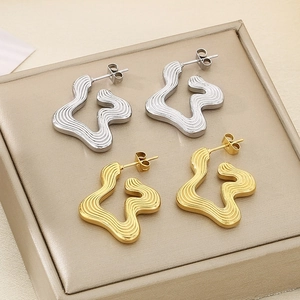 Macro detail of wave-textured geometric stud earrings in gold and silver finishes