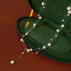 Detailed view of pearl necklace with unique Y-shaped design in green velvet jewelry box