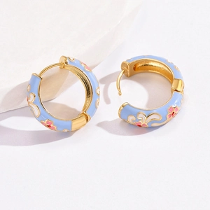 Detail of floral enamel hoop earrings with light blue finish and pink flower patterns