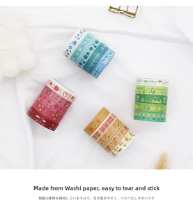 Close-up of decorative washi tape rolls with floral and fruit patterns on white cloth