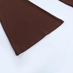 Detail shot showing the flared leg hem of dark brown slim-fit jumpsuit trousers