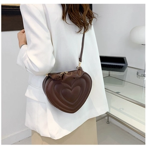 Detail of vintage heart-shaped brown leather crossbody bag with pleated edge on model