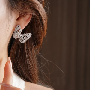 Macro detail of a silver butterfly earring with intricate micro-paved zircons on model
