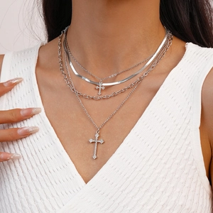 Macro view of multi-layered silver necklace featuring diamond-encrusted cross pendant