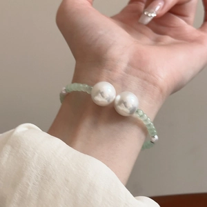 Close-up of minimalist beaded bracelet with light green glass beads and two large pearls