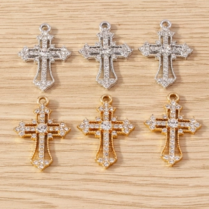 Golden and silver metal cross pendants with rhinestones on a natural wood background
