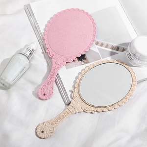 Vintage embossed handheld makeup mirrors in pink and beige with ornate floral handles