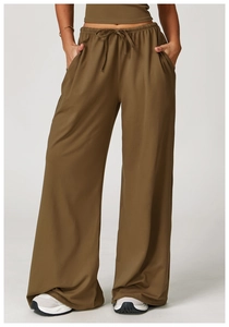 Detail of olive green wide-leg trousers showing waist drawstring and side pocket texture